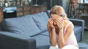 Honte et culpabilité toxique chez une personne hypersensible assise, cachant son visage, illustrant la souffrance intérieure